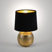 Lampa stołowa z abażurem czarno-złota zaświecona widoczna od przodu.
