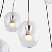 Zbliżenie transparentnych szklanych kloszy z metalowymi, złotymi oprawami i świecącymi źródłami światła.
