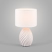 Lampa stołowa biała zaświecona widoczna od przodu na szarym tle.