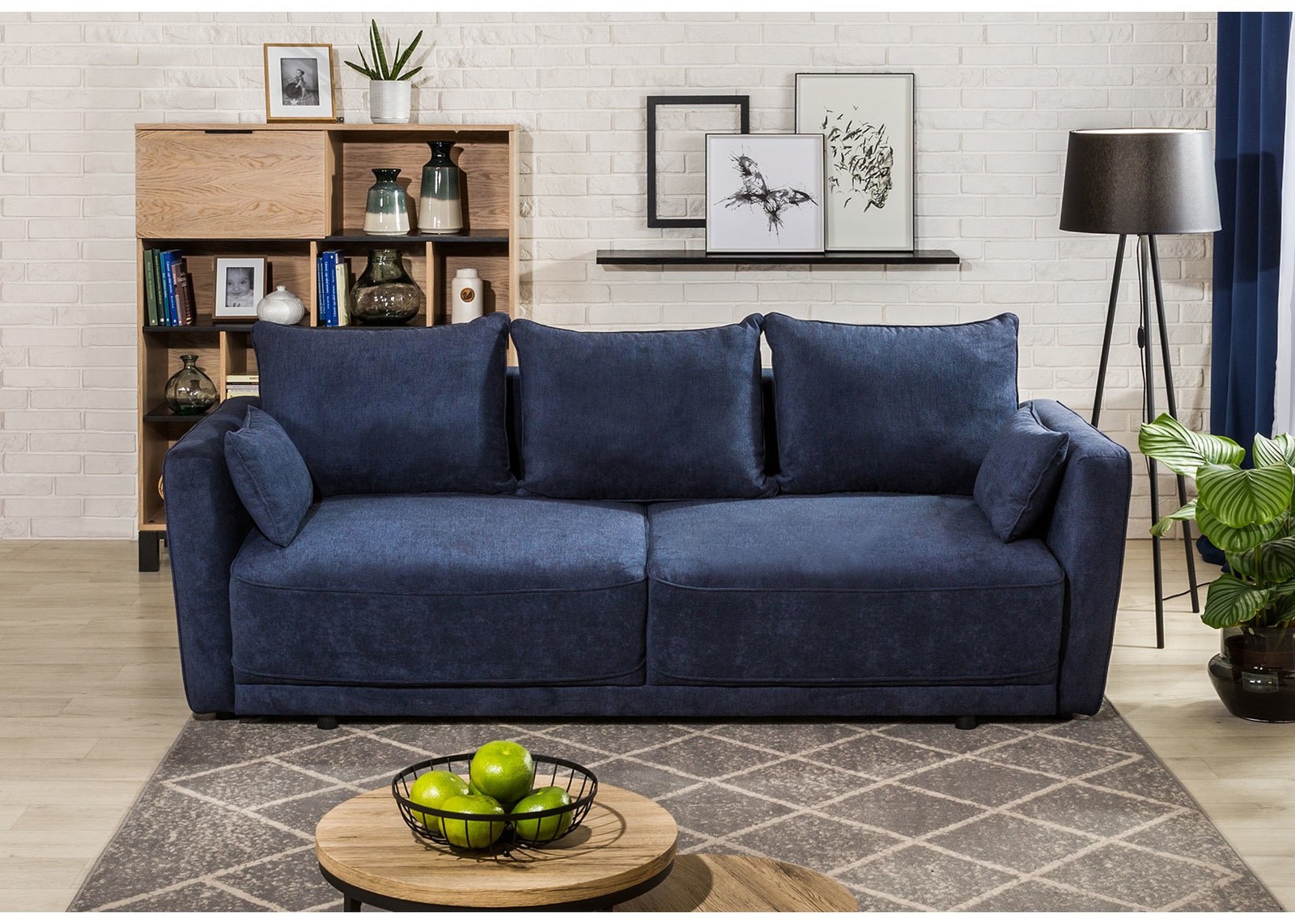 Granatowa sofa z regałem i lampą podłogową