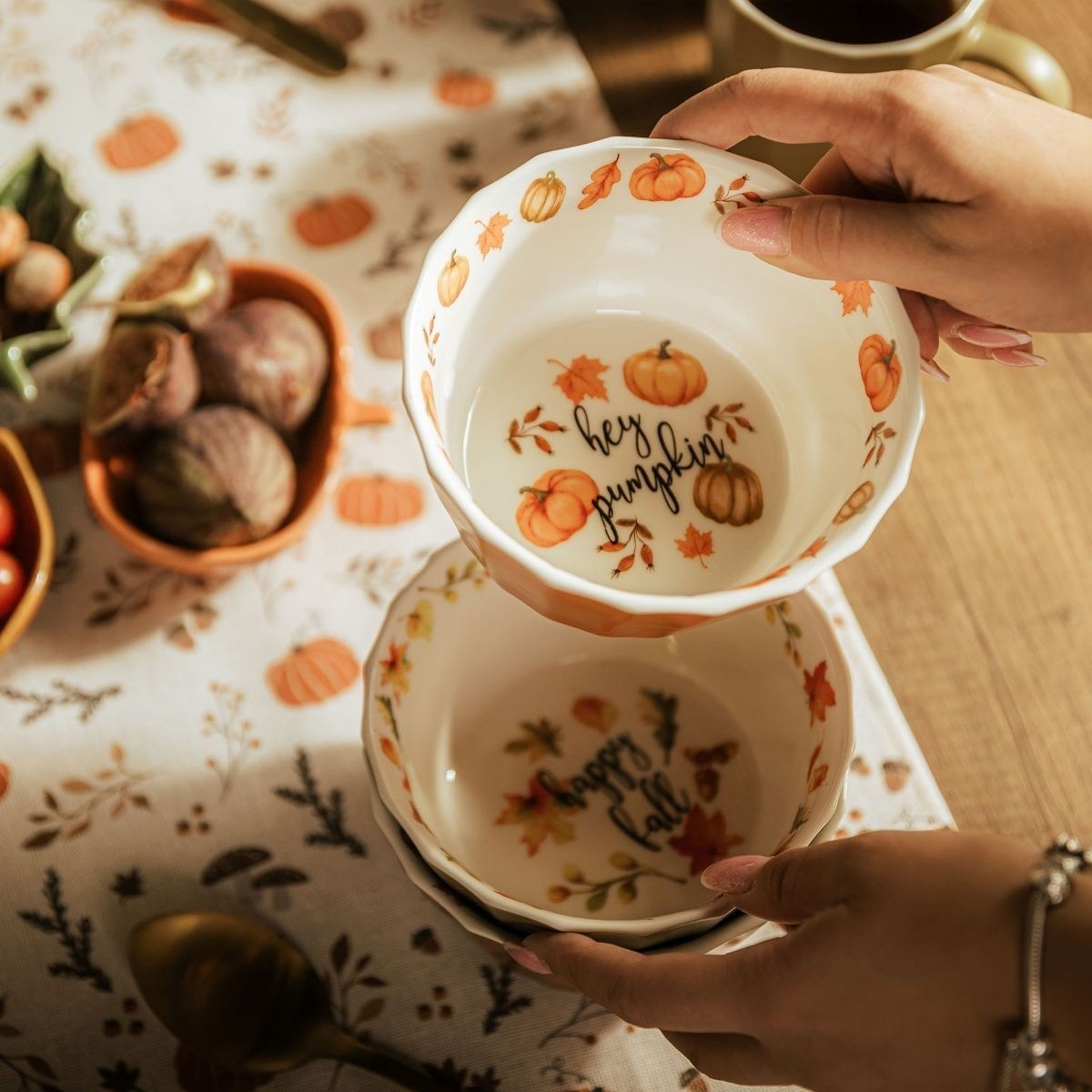 Dwie ceramiczne miski z jesiennymi motywami i napisami „Happy Fall” oraz „Hey Pumpkin”, prezentowane na zastawionym stole.
