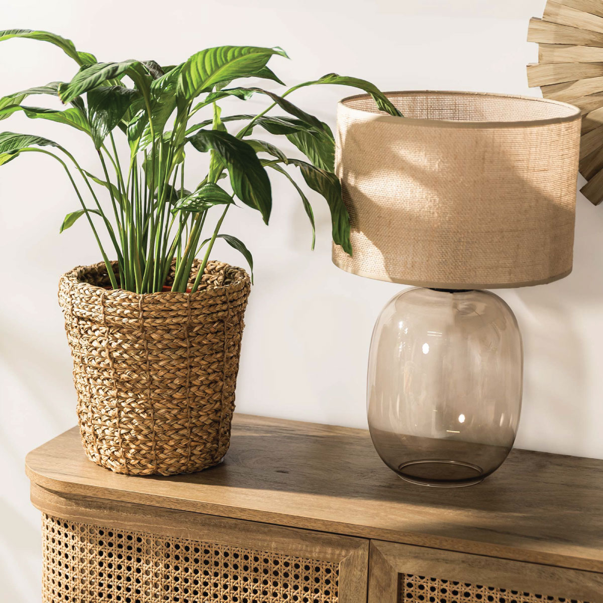 Pleciony kosz Nest Natural z trawy morskiej oraz lampa Melody z jutowym abażurem jako naturalne dodatki do przytulnego salonu w stylu etno.