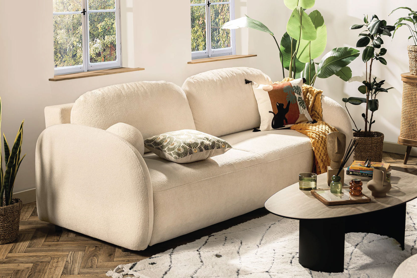 Beżowa sofa Roma z dekoracyjnymi poduszkami oraz poszewką Cats w przytulnym salonie etno.