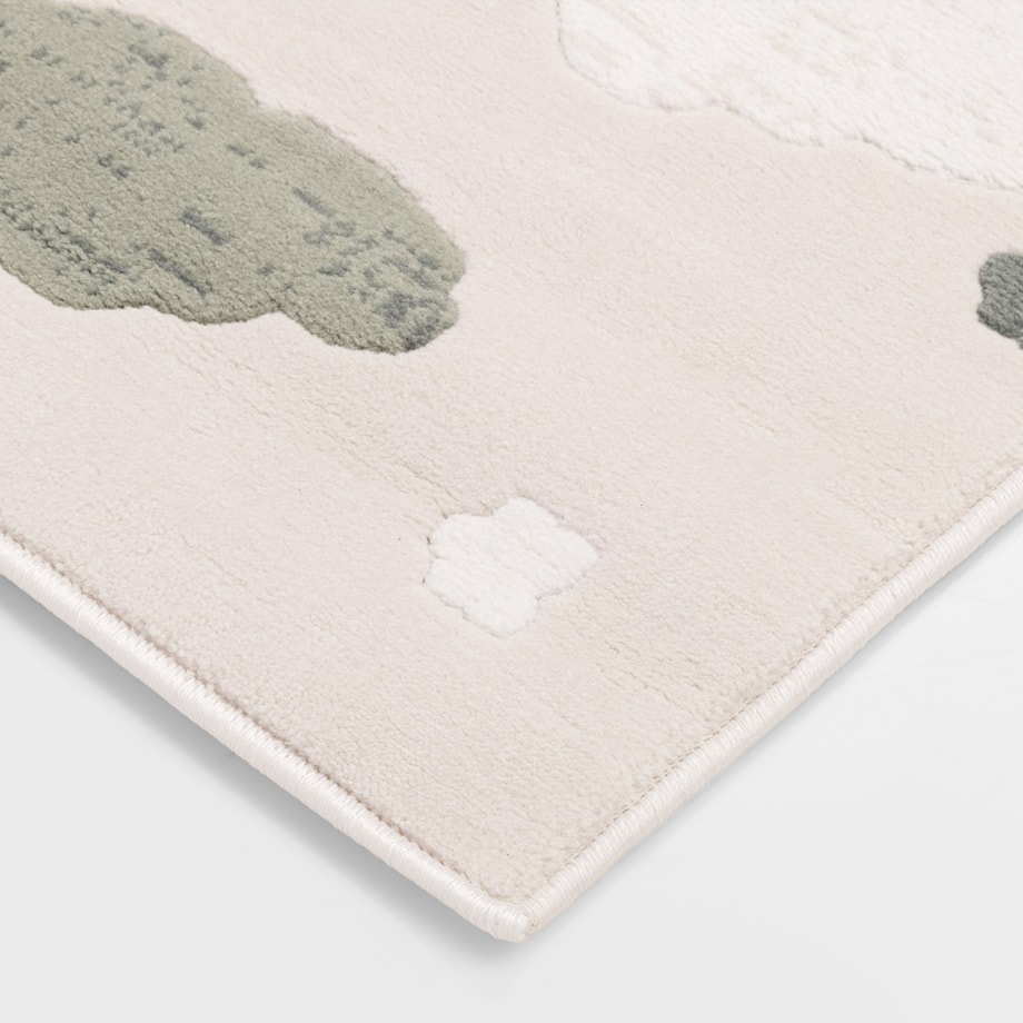 Zbliżenie dywanu dziecięcego z wzorem chmur i gwiazdek w odcieniach beżu, zieleni i kremu.
