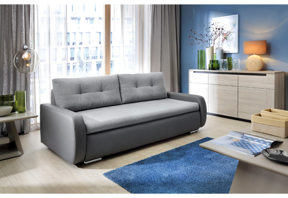Szara sofa rozkładana obok jasnej komody.