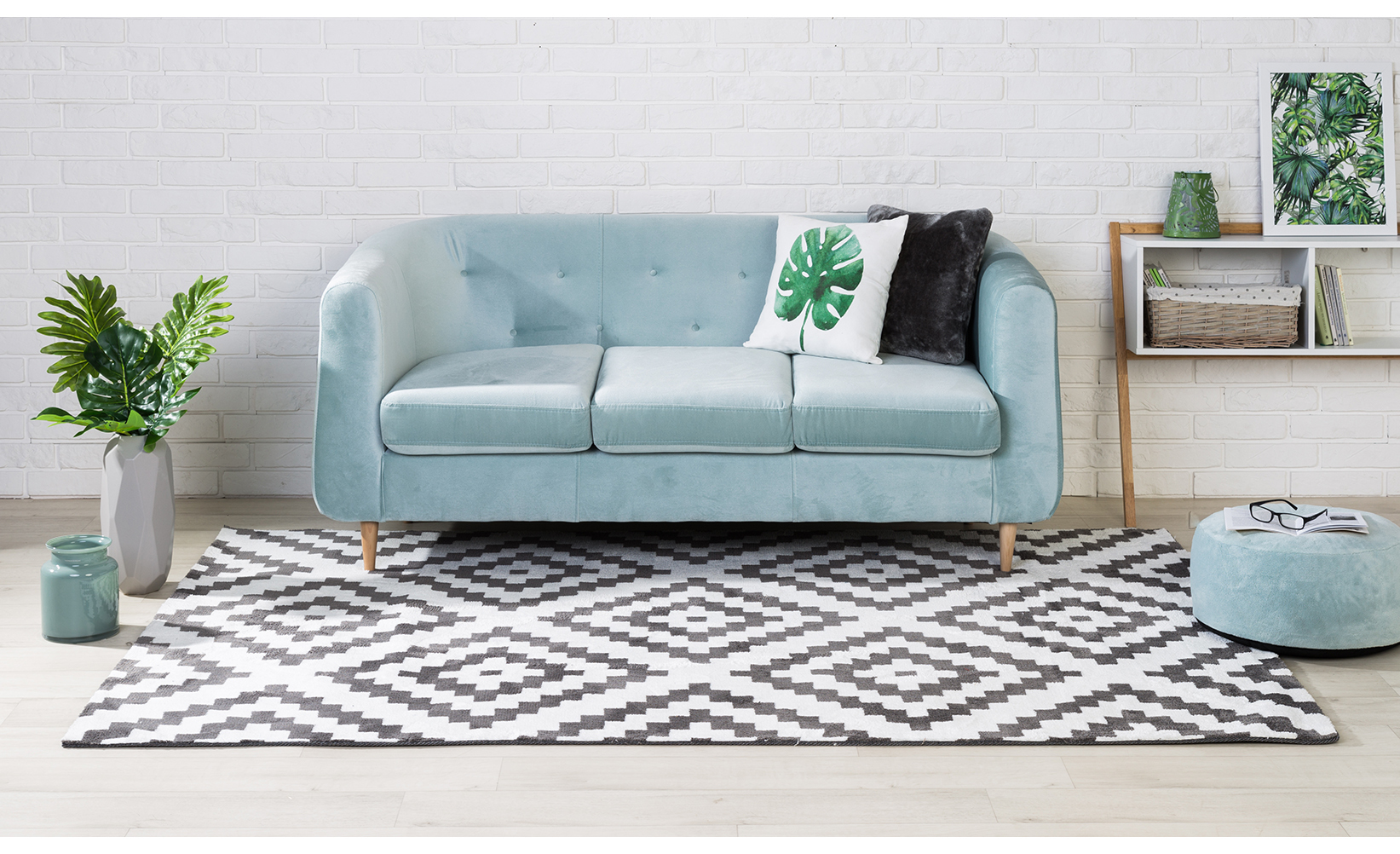 Sofa w jasnoniebieskim kolorze w aranżacji nowoczesnego salonu z dywanem we wzór geometryczny