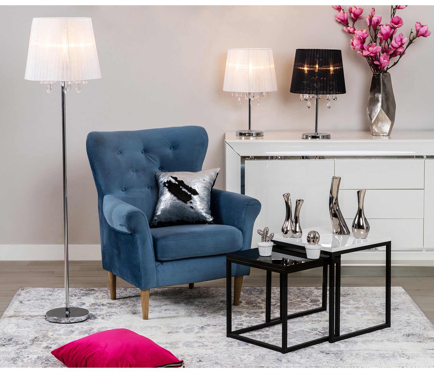 Niebieski fotel uszak z dekoracyjną poduszką w eleganckiej aranżacji salonu glamour z białą komodą.