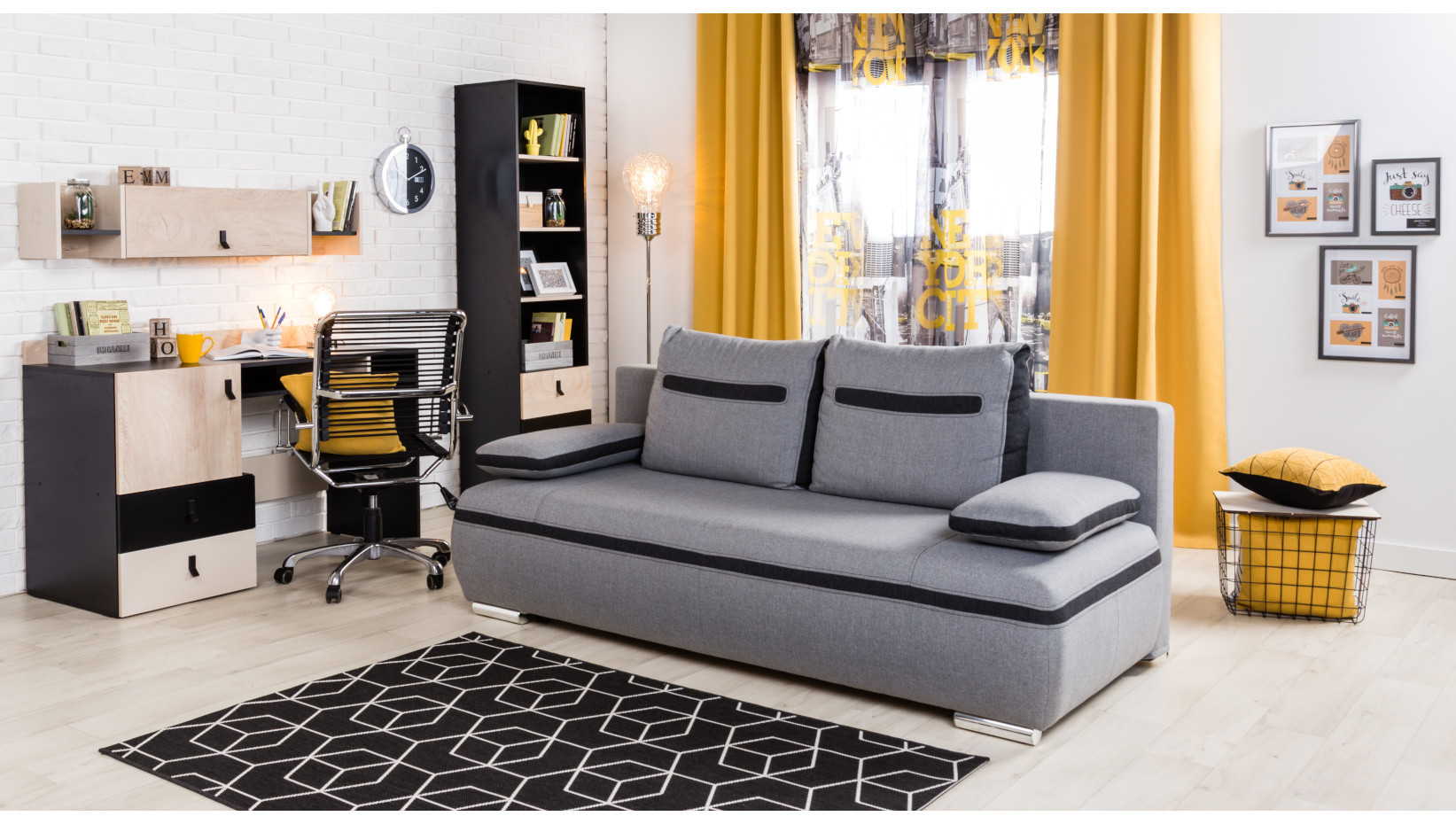Szara sofa rozkładana w nowoczesnym pokoju młodzieżowym z biurkiem, regałem i funkcjonalnymi meblami.