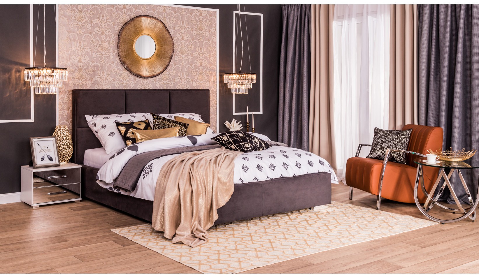 Elegancka sypialnia glamour z tapicerowanym łóżkiem, kryształowymi lampami, okrągłym lustrem i brązowym fotelem przy oknie.