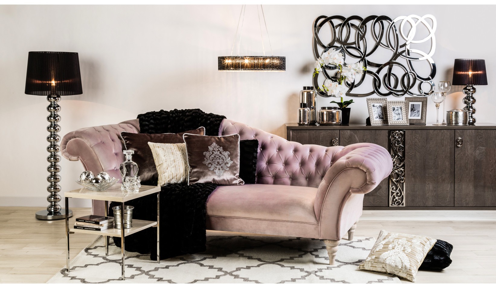 Salon w stylu glamour z pudroworóżową sofą Chesterfield, czarnymi lampami i eleganckimi dodatkami