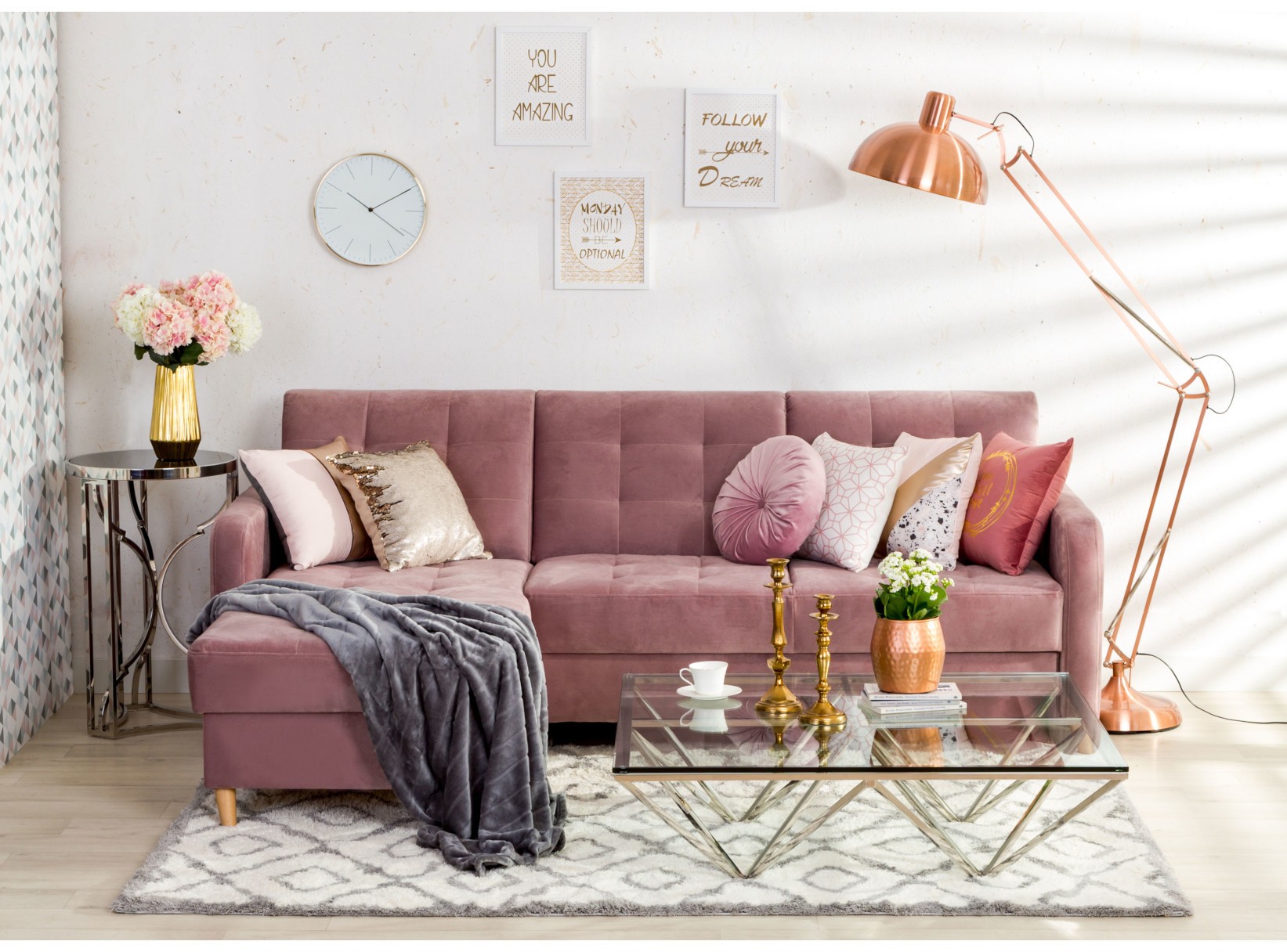 Pudrowa pikowana sofa i miedziana lampa łukowa