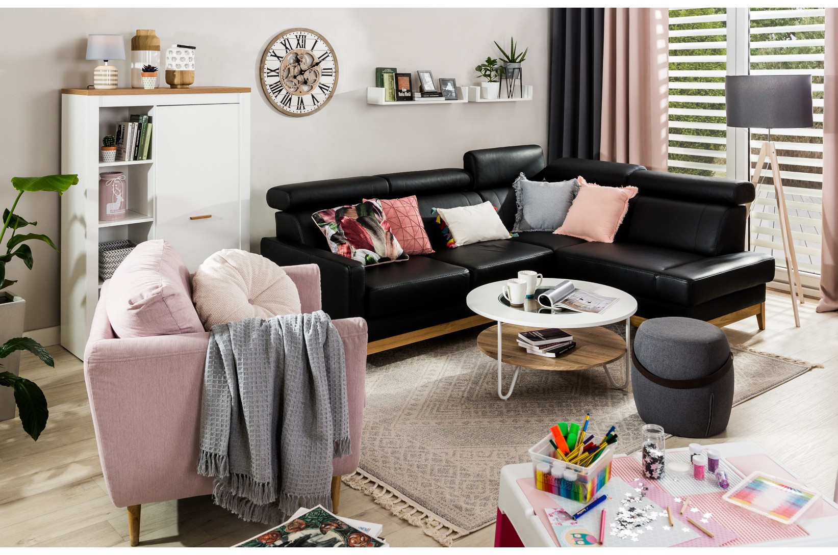 Czarna sofa skórzana i różowy fotel w jasnym pokoju
