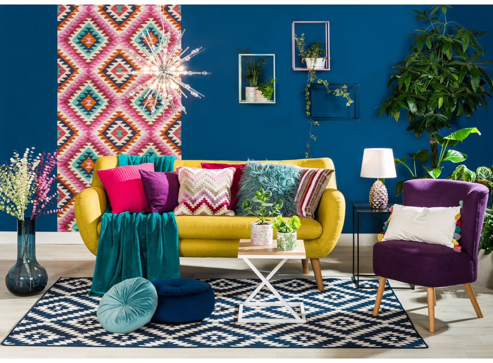 Kolorowy salon w stylu boho z żółtą sofą, fioletowym fotelem i granatową ścianą