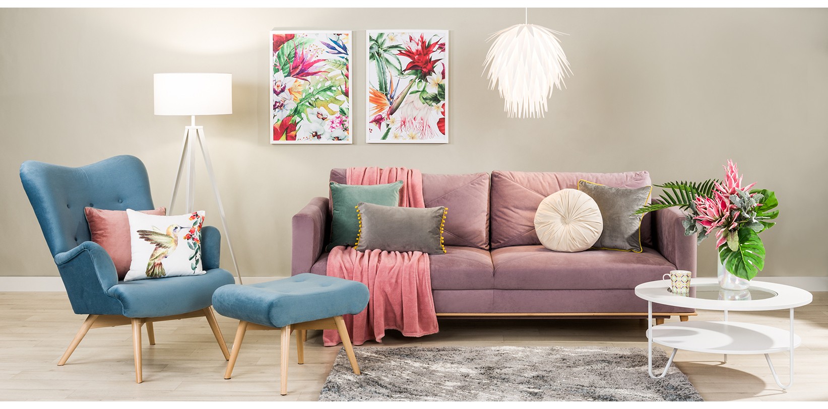 Pudrowa sofa i niebieski fotel z podnóżkiem.