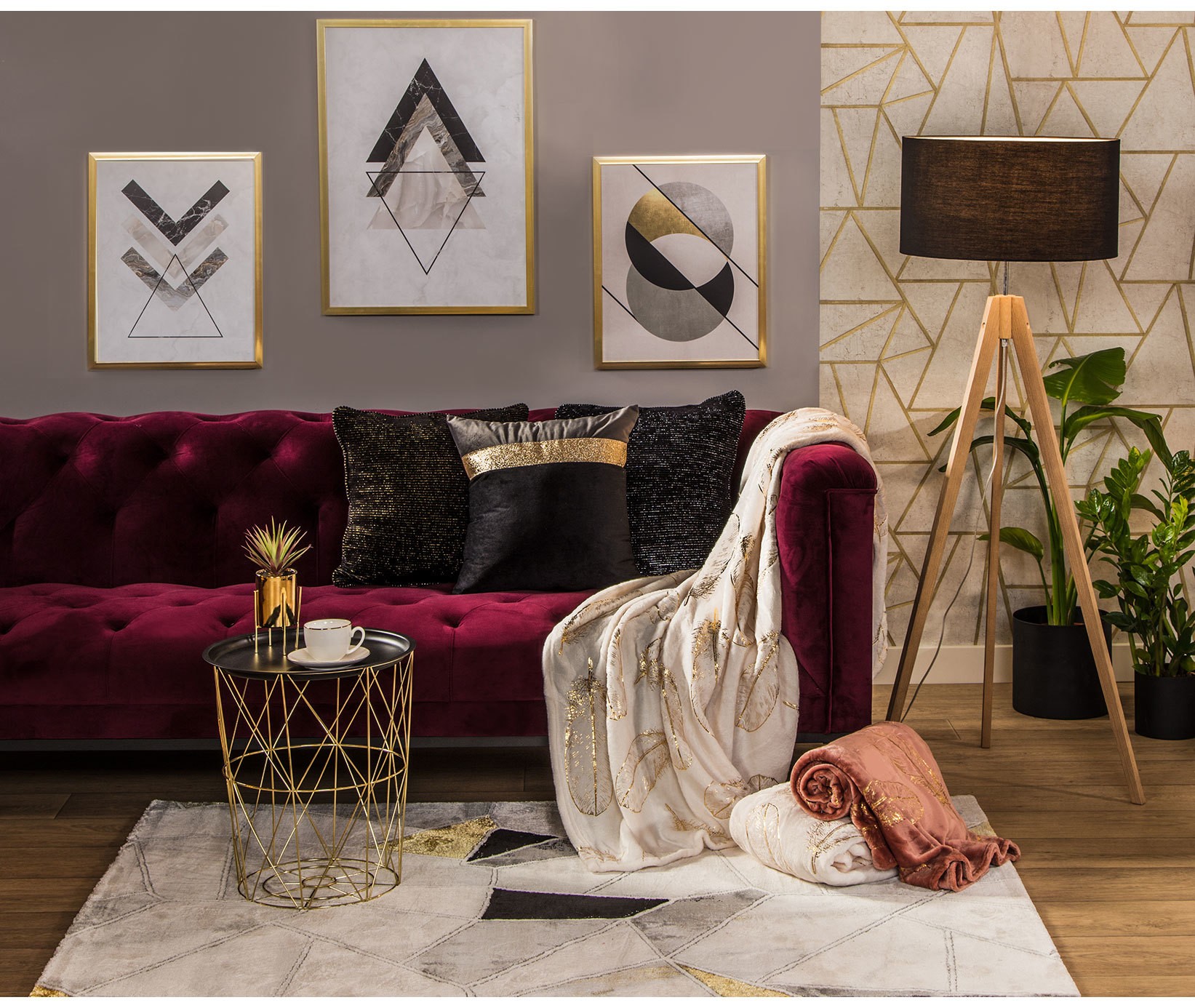Bordowa pikowana sofa z geometrycznymi plakatami