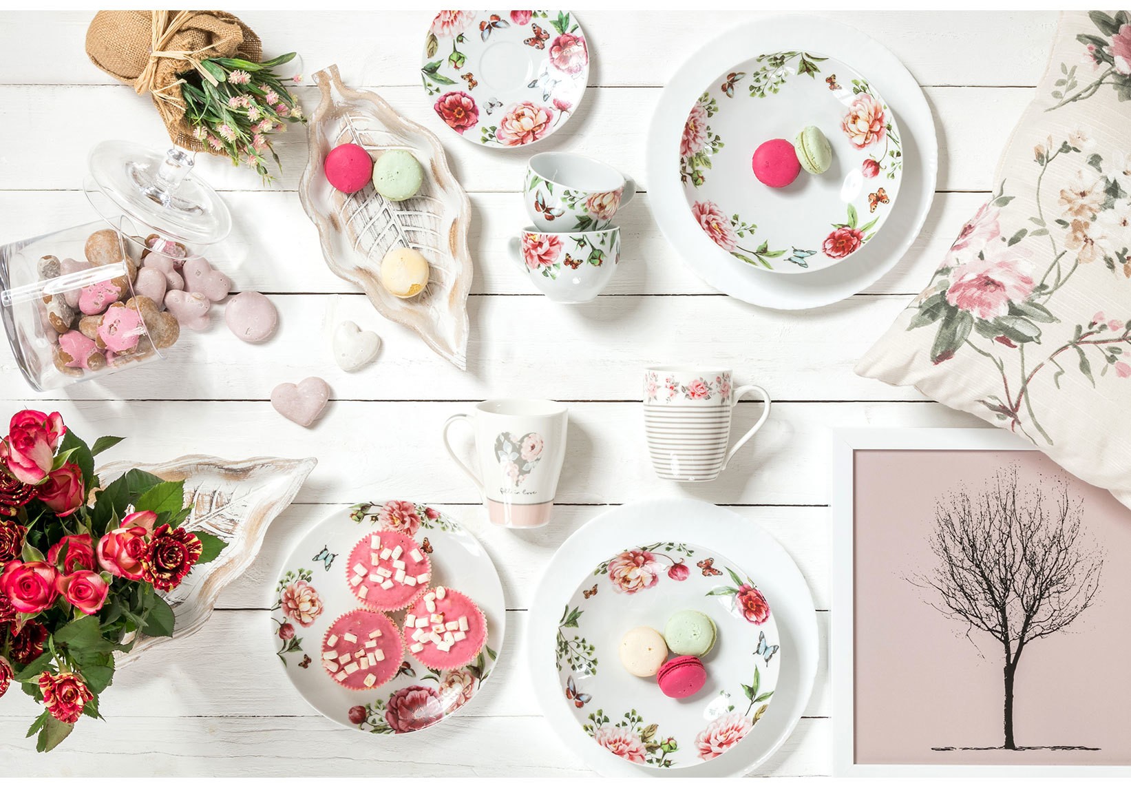 Kolekcja porcelany w kwiatowy wzór z talerzami, kubkami i filiżankami w romantycznej aranżacji z makaronikami i różami.