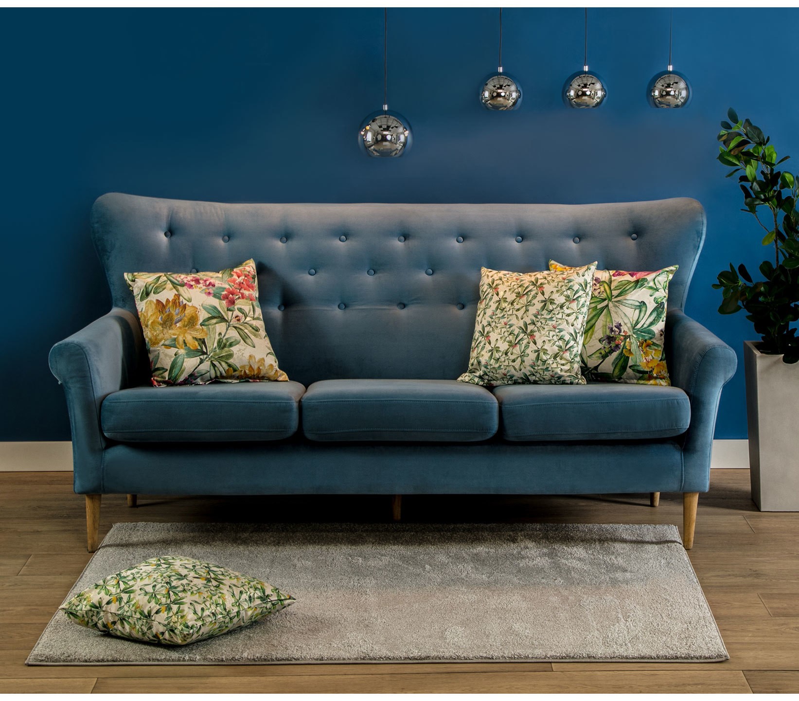 Niebieska pikowana sofa przy granatowej ścianie
