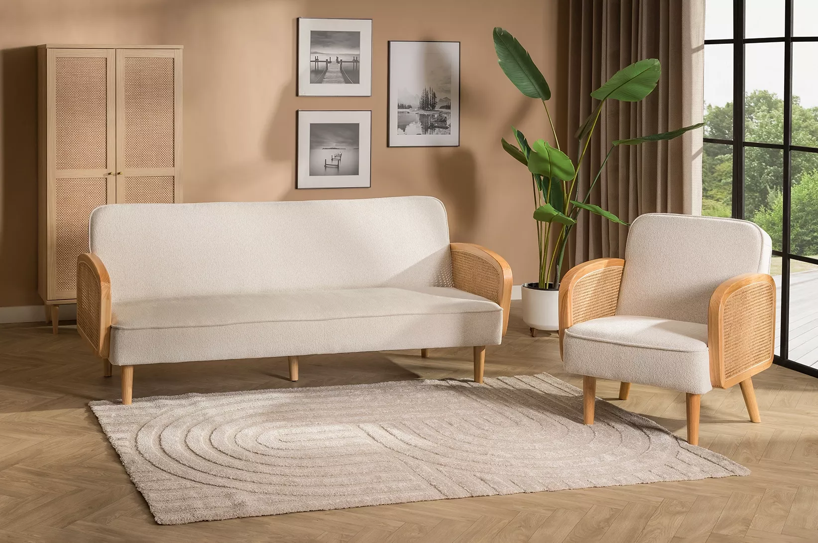 Jasna sofa i fotel z rattanowymi bokami w salonie w stylu boho z drewnianymi meblami i roślinami doniczkowymi.