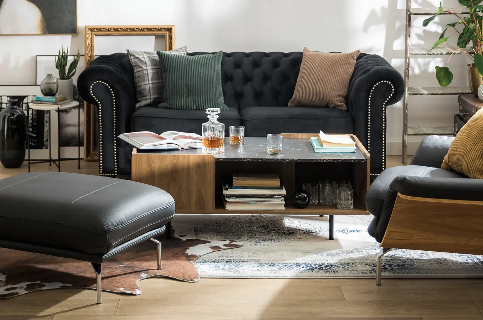 Nowoczesny salon z czarną sofą, skórzanym fotelem, podnóżkiem oraz drewnianym stolikiem kawowym w eleganckiej aranżacji wnętrza.