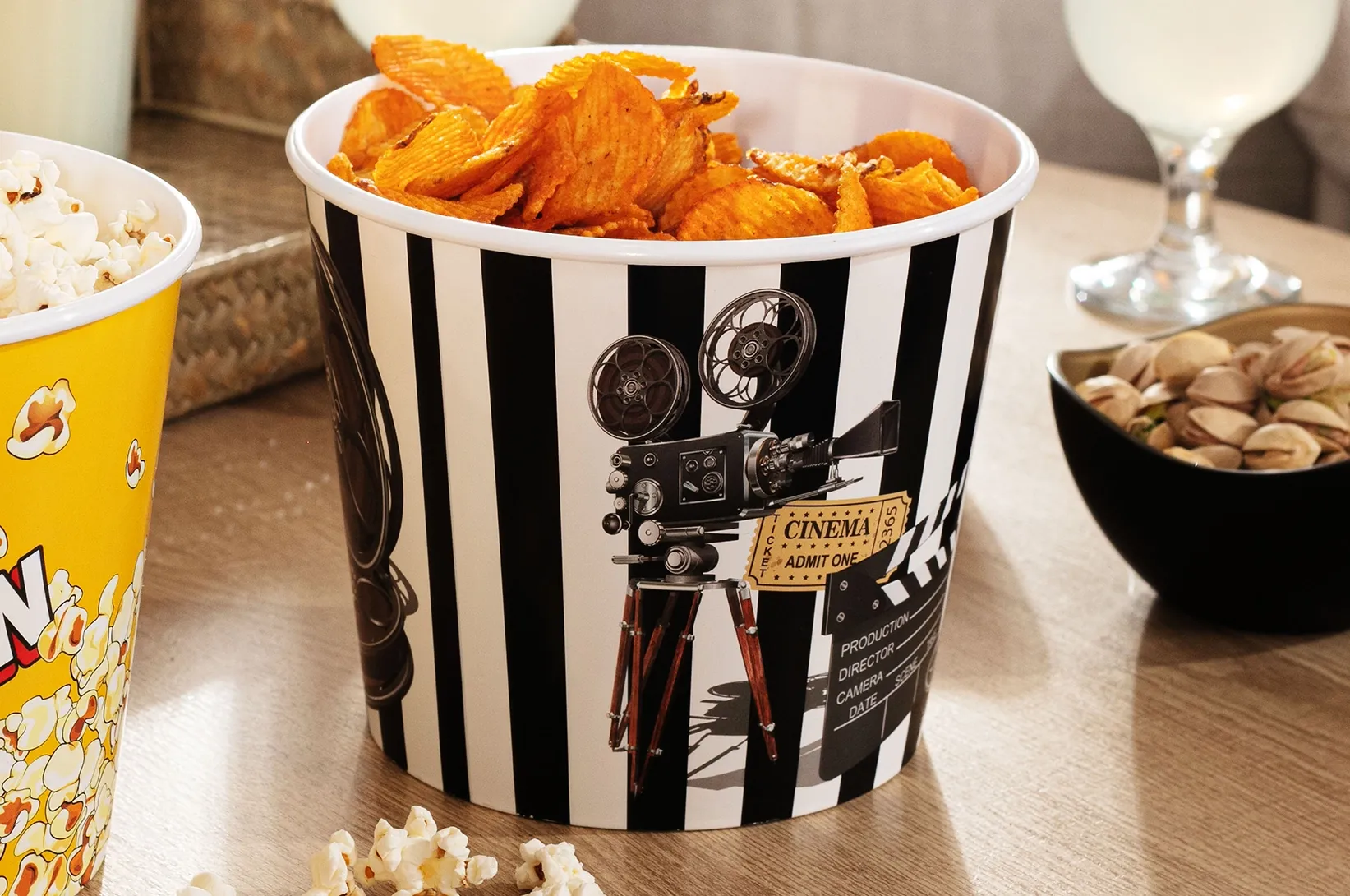 Miska na popcorn i pojemnik na przekąski w kinowym wzorze, wypełnione chipsami i popcornem, przygotowane na domowy seans filmowy.